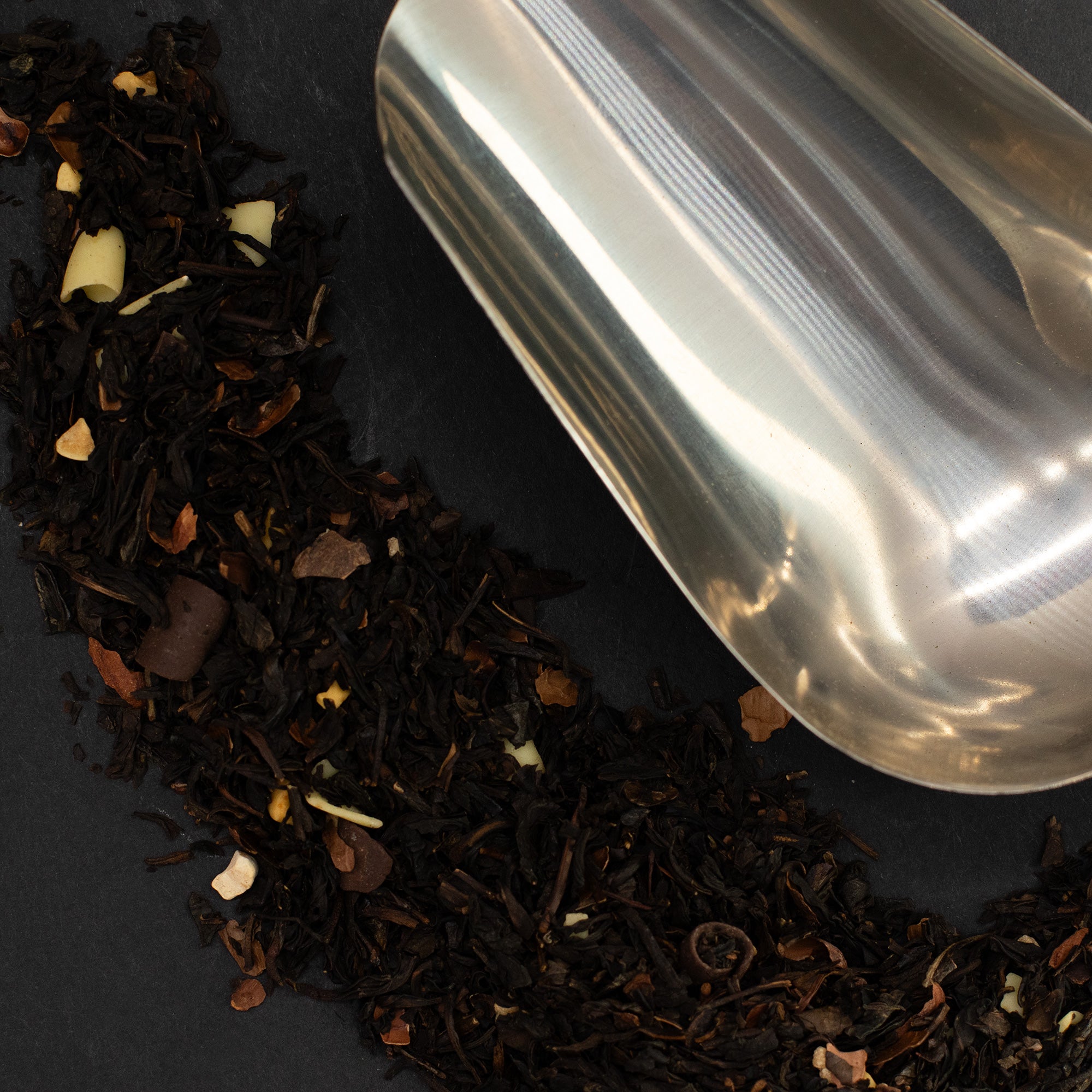 Detaliu ingrediente premium: frunze de ceai negru, coji de cacao, bucăți de ciocolată albă și migdale crocante.